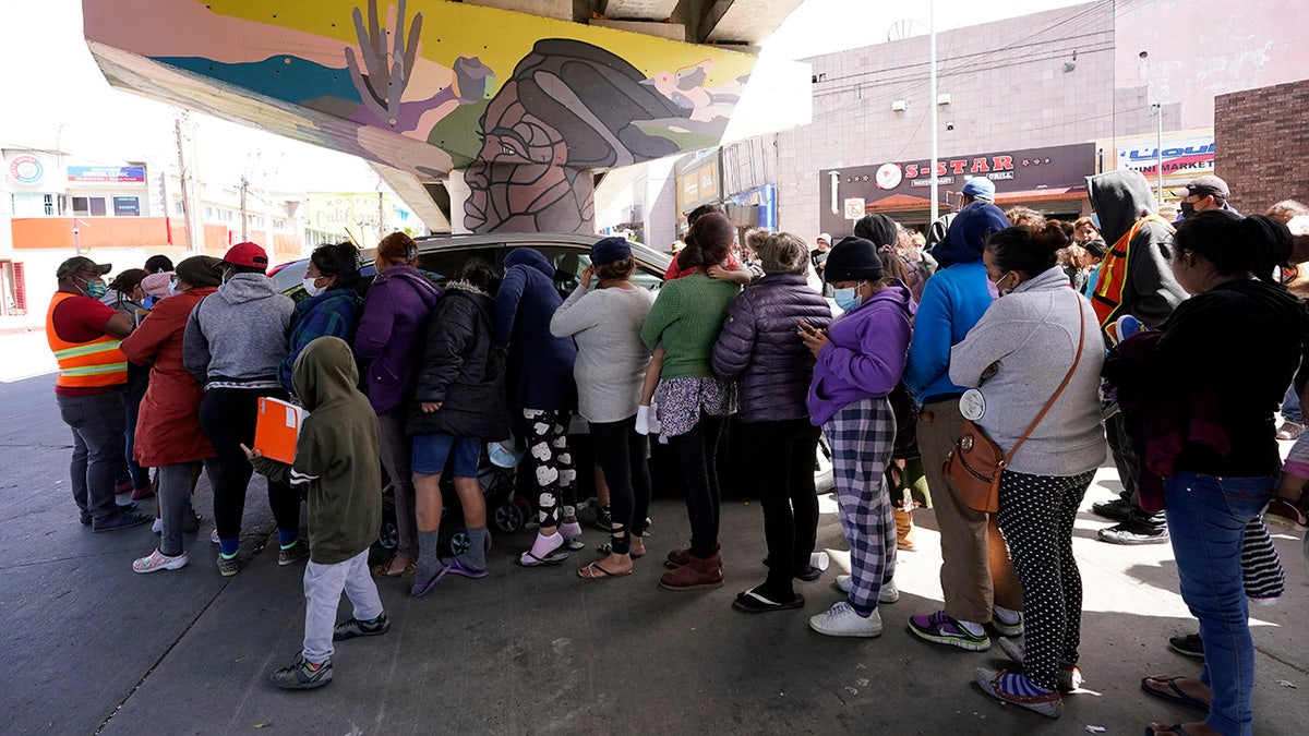 People surround a car as it arrives carrying food donations at a makeshift camp for migrants seeking asylum in the United States at the border crossing Friday, March 12, 2021, in Tijuana, Mexico. The Biden administration hopes to relieve the strain of thousands of unaccompanied children coming to the southern border by terminating a 2018 Trump-era order that discouraged potential family sponsors from coming forward to house the children. (AP Photo/Gregory Bull)