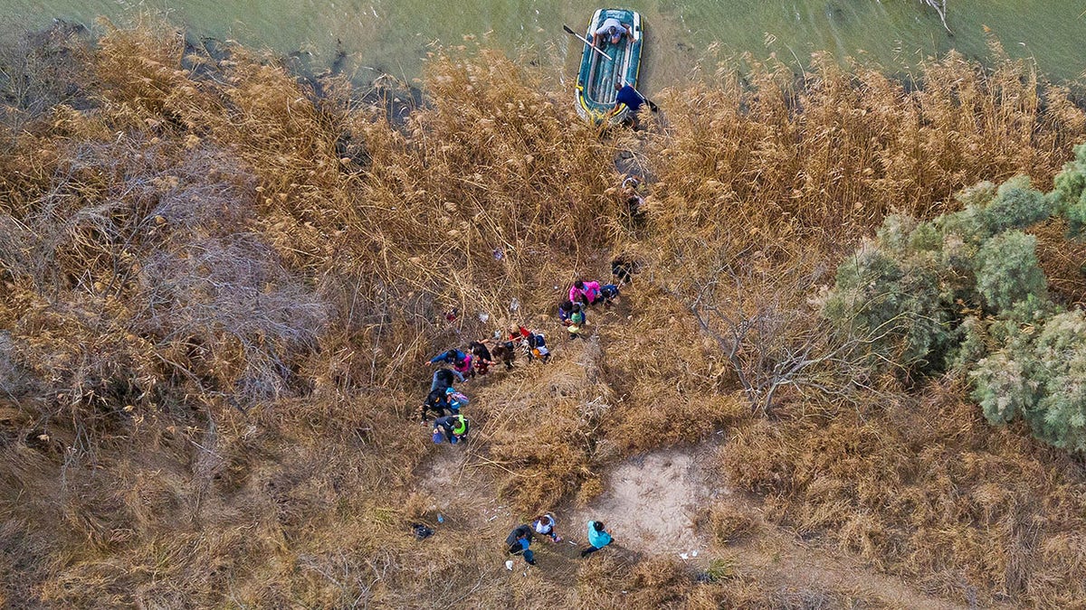 Migrant families and children climb the banks of the Rio Grande River into the United States as smugglers on rafts prepare to return to Mexico in Penitas, Texas, U.S., March 5, 2021. 