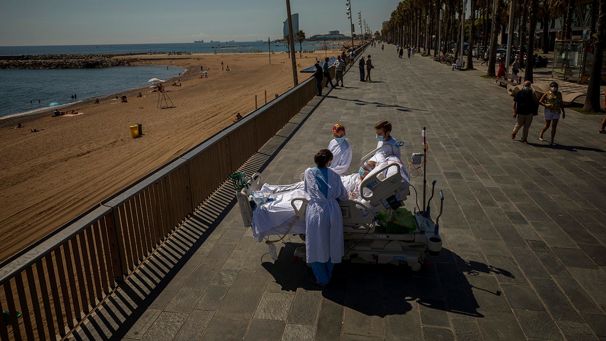 In this Sept. 4, 2020, file photo, Francisco Espana, 60, is surrounded by members of his medical team as he looks at the Mediterranean sea from a promenade next to the "Hospital del Mar" in Barcelona, Spain.
