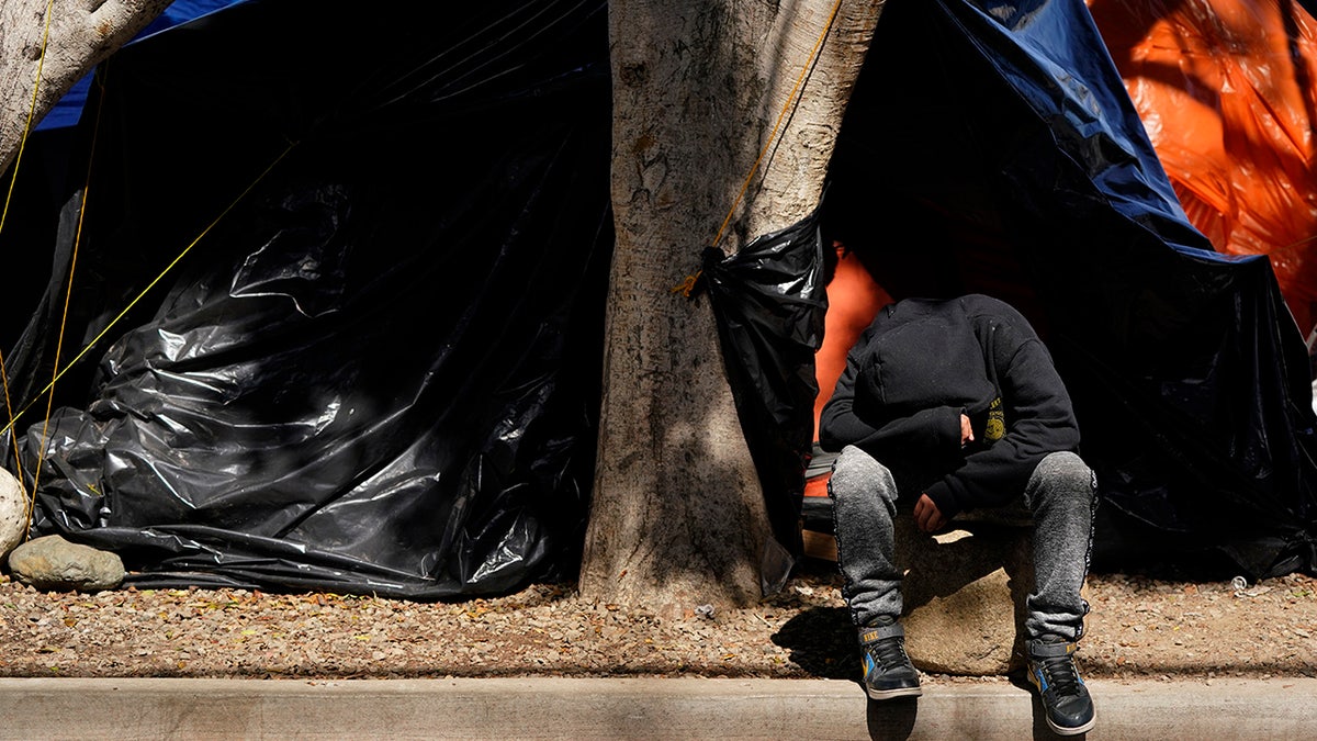 A boy sits in front of a tent housing several families at a makeshift camp of migrants at the border port of entry leading to the United States, Wednesday, March 17, 2021, in Tijuana, Mexico. (AP Photo/Gregory Bull)