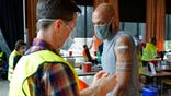 Shawn Brown, right, receives the second does of the Moderna COVID-19 vaccine from a volunteer worker at left, at a mass vaccination clinic at Seattle University, Friday, Feb. 26, 2021, in Seattle. Brown got his first dose of the vaccine in January after a broken freezer storing the vaccine led to an urgent call over social media and other channels for people to rush in and be vaccinated before the doses expired. As states ramp up vaccination distribution in the fight against the coronavirus, volunteers are needed to do everything from direct traffic to check people in to keep vaccination sites running smoothly. In return for their work, they're often given a shot — including those who are young and healthy and may not have otherwise been able to receive the shot until later in the year. (AP Photo/Ted S. Warren)
