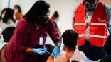FILE - In this March 17, 2021, file photo, health worker administers a dose of a Pfizer COVID-19 vaccine during a vaccination clinic at the Grand Yesha Ballroom in Philadelphia. More than three months into the U.S. vaccination drive, many of the numbers paint an increasingly encouraging picture as dozens of states have thrown open vaccinations to all adults or are planning to do so in a matter of weeks. (AP Photo/Matt Rourke, File)