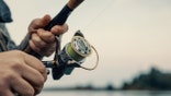 Fishing rod with a spinning reel in the hands of a fisherman. Fishing background.