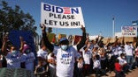 Migrants from Central America and other nationalities, hoping to cross and request asylum in the U.S., hold banners and shout slogans to U.S. President Joe Biden at their campsite outside El Chaparral border crossing, in Tijuana, Mexico February 27, 2021. REUTERS/Jorge Duenes