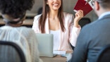 The travel agent keeps tickets for the plane in the travel agency. She offers them to clients. Couple at the travel agency office prepairing for a summer vacation. Concept for travel agent.