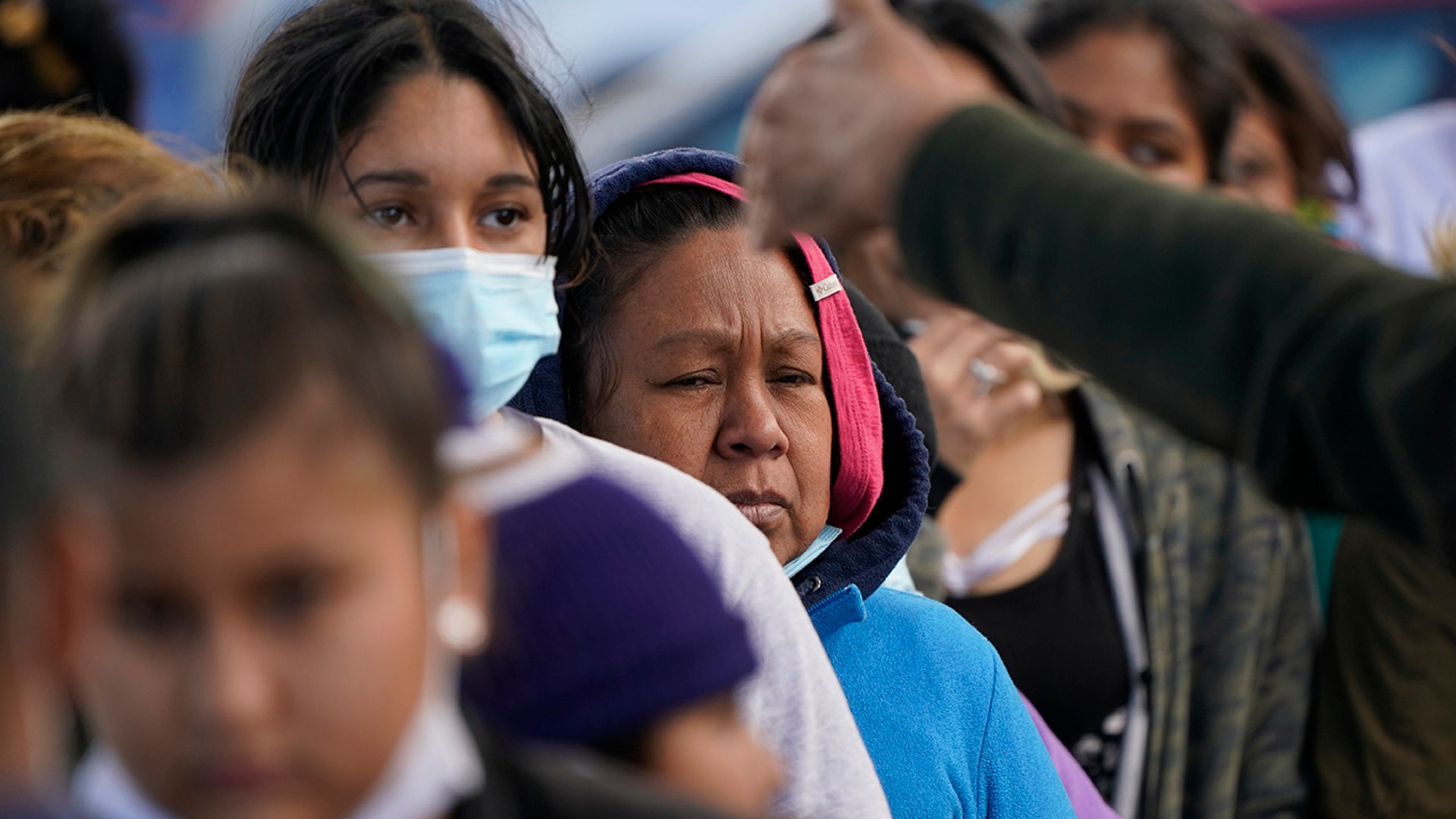 Migrant women are asked to line up for a free meal at a makeshift camp at the border port of entry leading to the United States on Friday, March 12, 2021, in Tijuana, Mexico. The migrant camp shows how confusion has undercut the message from President Joe Biden that it’s not the time to come to the United States. Badly misinformed, some 1,500 migrants set up tents across the border from San Diego harbor in the hope that Biden will open entry briefly and without notice. (AP Photo/Gregory Bull)