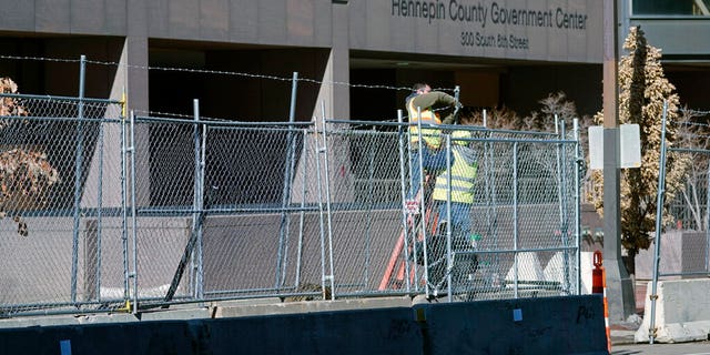 Workers install barbed wire on fencing outside the Hennepin County Government Center, Wednesday, Feb. 23, 2021 in Minneapolis, as part of security preparation for the trial of former Minneapolis police officer Derek Chauvin.