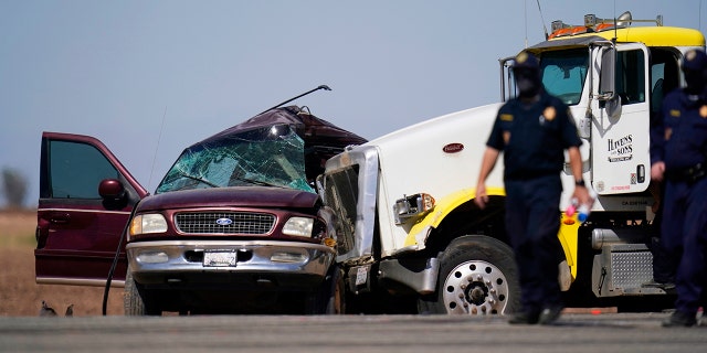 Law enforcement officers work at the scene of a deadly crash in Holtville, Calif., on Tuesday, March 2, 2021. Authorities say a semi-truck crashed into an SUV carrying 25 people on a Southern California highway, killing at least 13 people. (AP Photo/Gregory Bull)