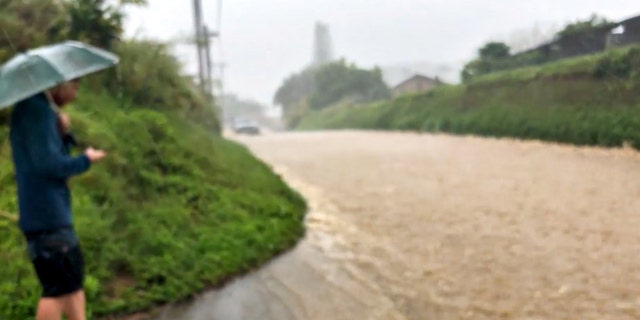 People look at a flooded street near the breached Kaupakalua dam, in Haiku on Maui, Hawaii, U.S. March 8, 2021, in this still image from a social media video. WWW.MONKEYSWITHDRUMS.COM via REUTERS
