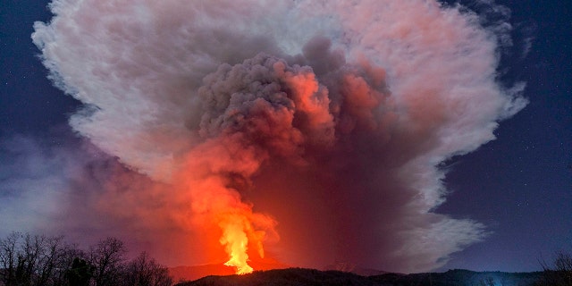 FILE - In this Wednesday, Feb. 24, 2021 file photo, a fiery river of glowing lava flows on the north-east side of the Mt. Etna volcano engulfed with ashes and smoke near Milo, Sicily. (AP Photo/Salvatore Allegra, File )