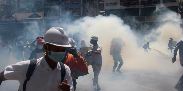 Anti-coup protesters run away from tear gas launched by security forces in Yangon, Burma, Monday, March 1, 2021. Defiant crowds returned to the streets of Burma's biggest city on Monday, determined to continue their protests against the military's seizure of power a month ago, despite security forces having killed at least 18 people around the country just a day earlier. (AP Photo)