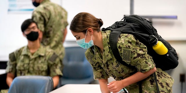 A midshipman uses a sanitizing wipe to clean her desk before the start of a leadership class at the U.S. Naval Academy in Annapolis, Md. (AP Photo/Julio Cortez, File)