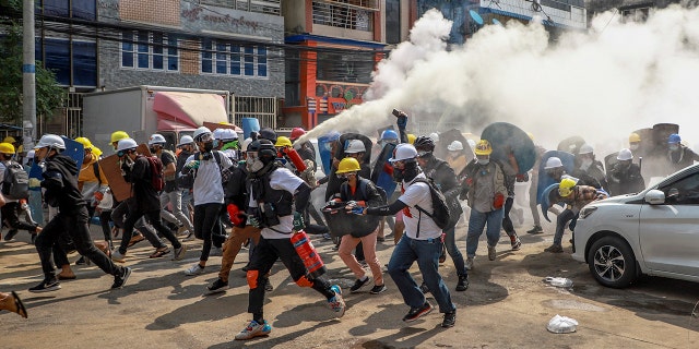Anti-coup protesters run as one of them discharges a fire extinguisher to counter the impact of tear gas fired by riot policemen in Yangon, Burma, Wednesday, March 3, 2021. Demonstrators in Burma took to the streets again on Wednesday to protest last month's seizure of power by the military. (AP Photo)