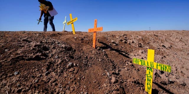 Hugo Castro leaves crosses at the scene of a deadly crash in Holtville, Calif., Tuesday, March 2, 2021. Authorities say a semitruck crashed into an SUV, killing multiple people. (AP Photo/Gregory Bull)