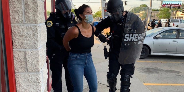 Police officers are being arrested for arresting Des Moines Register reporter Andrea Sahouri after a Black Lives Matter protest on May 31, 2020 in Des Moines, Iowa, was dispersed by tear gas.  (Photo courtesy of Katie Akin via AP)