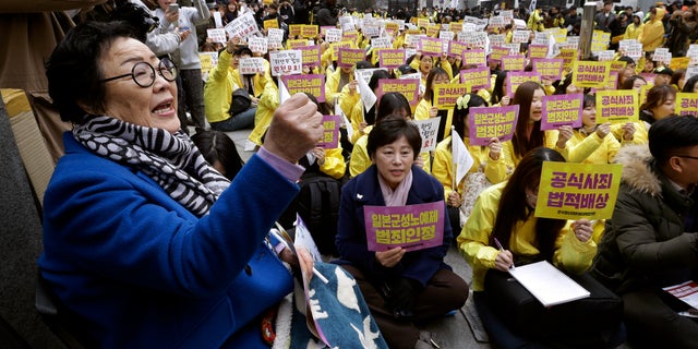 FILE - In this March 1, 2017, file photo, former "comfort woman" Lee Yong-soo, left, who was forced to serve for the Japanese troops as a sex slave during World War II, shouts slogans during a rally to mark the March First Independence Movement Day, the anniversary of the 1919 uprising against Japanese colonial rule, near the Japanese Embassy in Seoul, South Korea. Harvard University law professor J. Mark Ramseyer alleged in a December 2020 article, scheduled to appear in the March 2021 issue of the International Review of Law and Economics, that the Korean women had actually chosen to work as prostitutes. Lee described Ramseyer's claim as "ludicrous" and demanded an apology. (AP Photo/Ahn Young-joon, File)