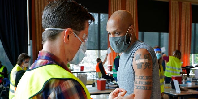 Shawn Brown, right, receives the second does of the Moderna COVID-19 vaccine from a volunteer worker at left, at a mass vaccination clinic at Seattle University, Friday, Feb. 26, 2021, in Seattle. (AP Photo/Ted S. Warren)