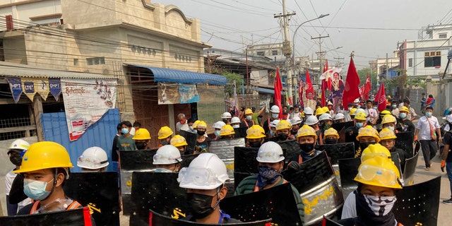 Protesters march with makeshift shields on a main road during a demonstration in Mandalay, Burma, Monday, March 8, 2021. Large protests have occurred daily across many cities and towns in Burma. (AP Photo)