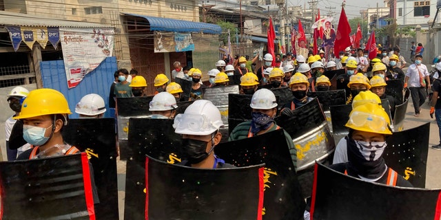 Protesters march with makeshift shields on a main road during a demonstration in Mandalay, Burma, Monday, March 8, 2021. Large protests have occurred daily across many cities and towns in Burma. (AP Photo)