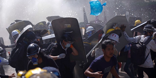 Protesters are dispersed as riot police fire tear gas during a demonstration in Yangon, Burma, Monday, March 8, 2021. (AP Photo)