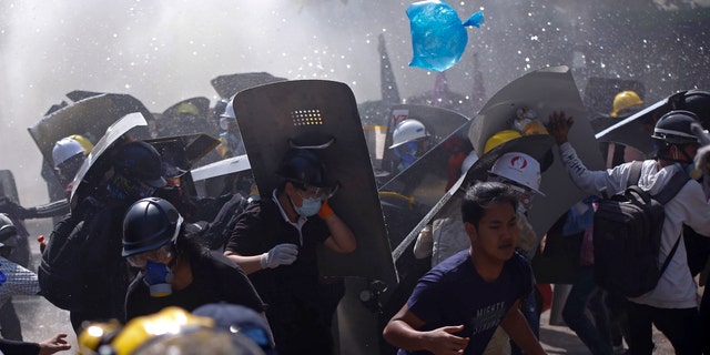 Protesters are dispersed as riot police fire tear gas during a demonstration in Yangon, Burma, Monday, March 8, 2021. (AP Photo)