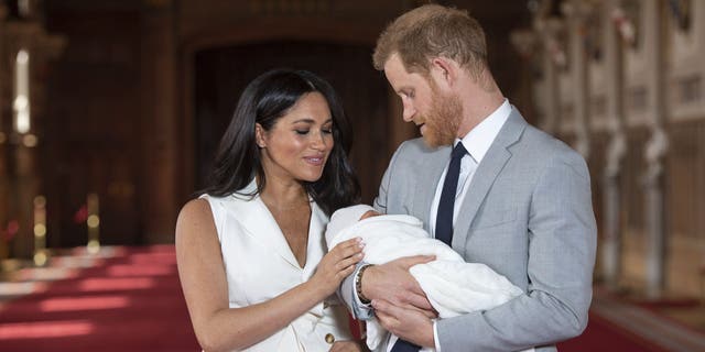 FILE - In this Wednesday May 8, 2019 file photo, Britain's Prince Harry and Meghan, Duchess of Sussex, pose during a photocall with their newborn son Archie, in St George's Hall at Windsor Castle, Windsor, south England. One of the most dramatic claims in Prince Harry and Meghan's interview with Oprah Winfrey was that their son was denied a royal title, possibly because of the color of his skin. Queen Elizabeth II has nine great-grandchildren, including Archie. They are not princes and princesses, apart from the three children of Prince William, who is second in line to the throne and destined to be king one day. (Dominic Lipinski/Pool via AP, File)