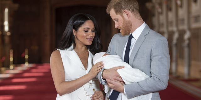 FILE - In this Wednesday May 8, 2019 file photo, Britain's Prince Harry and Meghan, Duchess of Sussex, pose during a photocall with their newborn son Archie, in St George's Hall at Windsor Castle, Windsor, south England. One of the most dramatic claims in Prince Harry and Meghan's interview with Oprah Winfrey was that their son was denied a royal title, possibly because of the color of his skin. Queen Elizabeth II has nine great-grandchildren, including Archie. They are not princes and princesses, apart from the three children of Prince William, who is second in line to the throne and destined to be king one day. (Dominic Lipinski/Pool via AP, File)