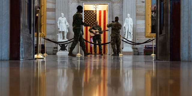 U.S. Army Michigan National Guard Sgt. Hannah Boulden, from Ann Arbor, Mich., plays her guitar and sings in the Rotunda of the U.S. Capitol, before the vote on the Democrat's $1.9 trillion COVID-19 relief bill, on Capitol Hill, Wednesday, March 10, 2021, in Washington. (AP Photo/Alex Brandon)