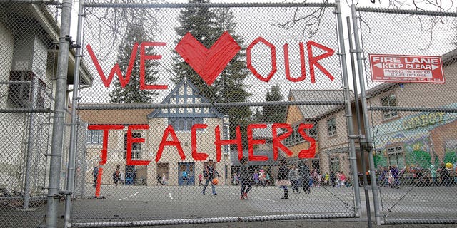 FILE: A sign supporting teachers is shown on a fence outside of Chabot Elementary School in Oakland, Calif. 