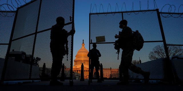 National Guard open a gate in the razor wire topped perimeter fence around the Capitol to allow another member in at sunrise in Washington, Monday, March 8, 2021. (AP Photo/Carolyn Kaster)