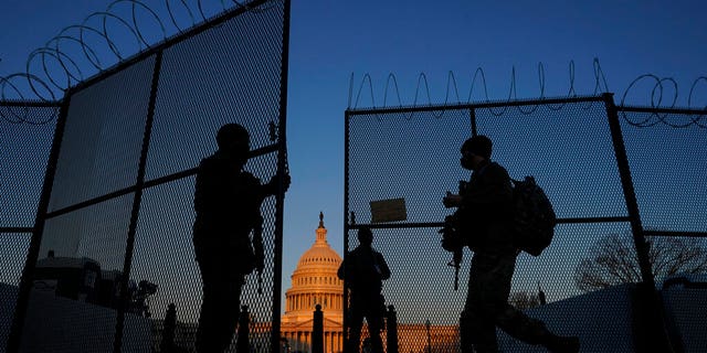 National Guard open a gate in the razor wire topped perimeter fence around the Capitol to allow another member in at sunrise in Washington, Monday, March 8, 2021. (AP Photo/Carolyn Kaster)