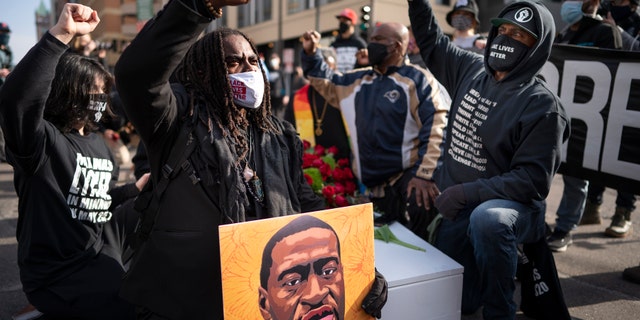 Cortez Rice, left, of Minneapolis, sits with others in the middle of Hennepin Avenue on Sunday, March 7, 2021, in Minneapolis, Minn., to mourn the death of George Floyd a day before jury selection is set to begin in the trial of former Minneapolis officer Derek Chauvin, who is charged in Floyd's death. (Jerry Holt/Star Tribune via AP, File)