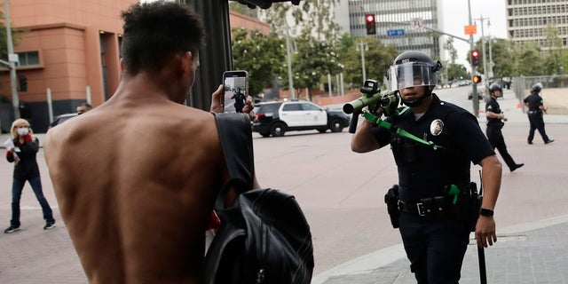 FILE - In this June 2, 2020, file photo, a police officer aims his less-lethal weapon at a demonstrator during a protest in Los Angeles, over the death of George Floyd on May 25 while in police custody in Minneapolis. (AP Photo/Jae C. Hong, File)