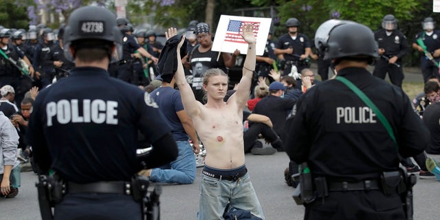 FILE - In this June 1, 2020, file photo, a protester raises his arm shortly before being arrested for violating a curfew in the Hollywood area of Los Angeles during demonstrations over the death of George Floyd. (AP Photo/Marcio Jose Sanchez, File)