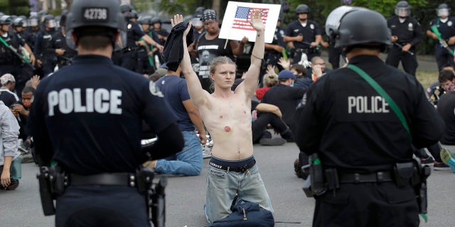 FILE - In this June 1, 2020, file photo, a protester raises his arm shortly before being arrested for violating a curfew in the Hollywood area of Los Angeles during demonstrations over the death of George Floyd. (AP Photo/Marcio Jose Sanchez, File)