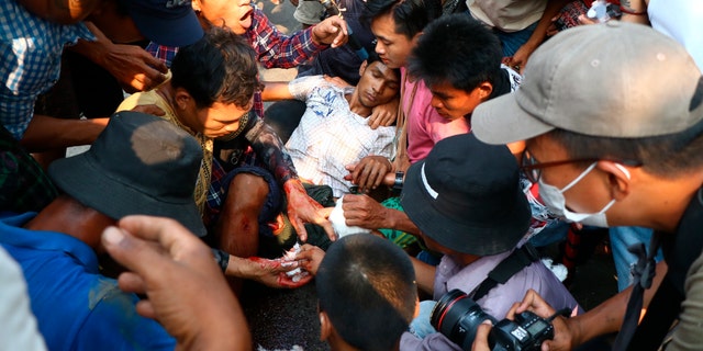 Anti-coup protesters surround an injured man in Hlaing Thar Yartownship in Yangon, Burma Sunday, March 14, 2021. A number of people were shot dead during protests in Burma's largest city on Sunday, as security forces continued their violent crackdown against dissent following last month's military coup. (AP Photo)