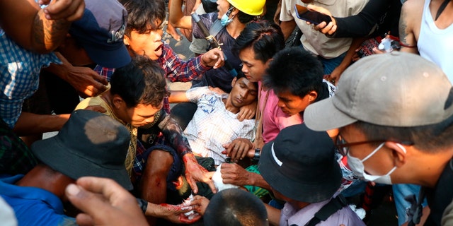 Anti-coup protesters surround an injured man in Hlaing Thar Yartownship in Yangon, Burma Sunday, March 14, 2021. A number of people were shot dead during protests in Burma's largest city on Sunday, as security forces continued their violent crackdown against dissent following last month's military coup. (AP Photo)