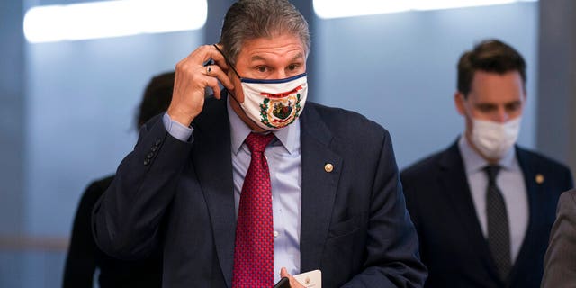 Sen. Joe Manchin, D-W.Va., adjusts his face mask as he arrives for votes on Biden administration nominees, at the Capitol in Washington, Tuesday, March 16, 2021.