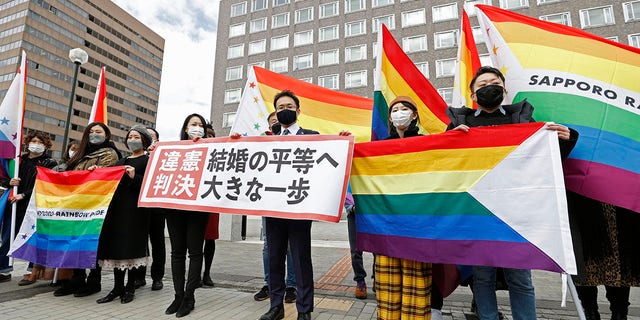 Plaintiffs' lawyers and supporters hold rainbow flags and a banner that reads: "Unconstitutional judgment" outside Sapporo District Court after a court rule, in Sapporo, northern Japan, Wednesday, March 17, 2021. The court ruled the government's ban on same-sex marriages is unconstitutional, recognizing the rights of same-sex couples for the first time in the only Group of Seven country that doesn't acknowledge their legal partnership. (Yohei Fukai/Kyodo News via AP)