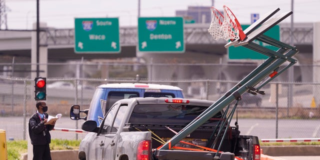 A security guard at the Kay Bailey Hutchison Convention Center checks in vehicles carrying basketball hoops Thursday, March 18, 2021, in Dallas. (AP Photo/LM Otero)