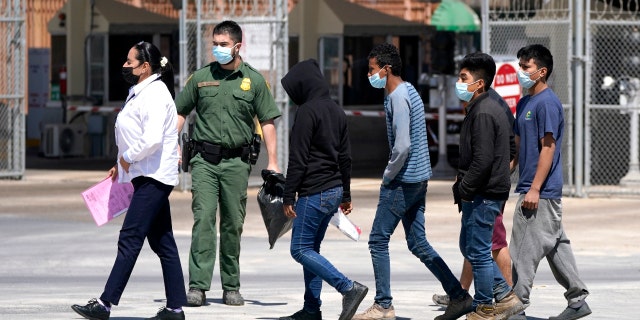 Migrants, who were caught trying to sneak into the U.S., are led by an U.S. Customs and Border Protection agent. (AP Photo/Julio Cortez)