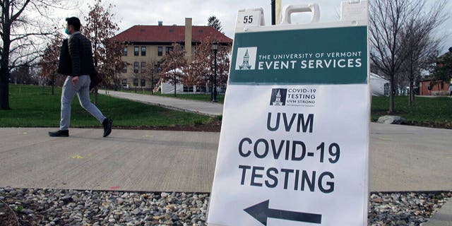 FILE: A University of Vermont student walks toward a tent leading to a COVID-testing site on campus in Burlington, Vt.