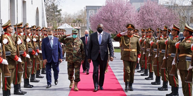 ADDS REFERENCE TO ACTING AFGHAN MINISTER OF DEFENSE YASIN ZIA - U.S. Defense Secretary Lloyd Austin, center, walks on the red carpet with Acting Afghan Minister of Defense Yasin Zia as they review an honor guard at the presidential palace in Kabul, Afghanistan, Sunday, March 21, 2021. Austin arrived in Kabul on his first trip to Afghanistan as Pentagon chief, amid swirling questions about how long American troops will remain in the country. (Presidential Palace via AP)