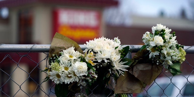 Bouquets line a fence put up around the parking lot where a mass shooting took place the day before in a King Soopers grocery store, Tuesday, March 23, 2021, in Boulder, Colo. (AP Photo/David Zalubowski)