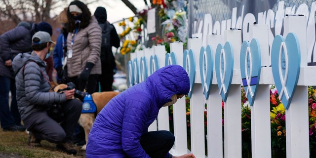 Adrienne Kroepsch of Golden, Colo., lights votive candles to place by crosses bearing the names of victims placed by the parking lot where a mass shooting took place in a King Soopers grocery store Tuesday, March 23, 2021, in Boulder, Colo. (AP Photo/David Zalubowski)