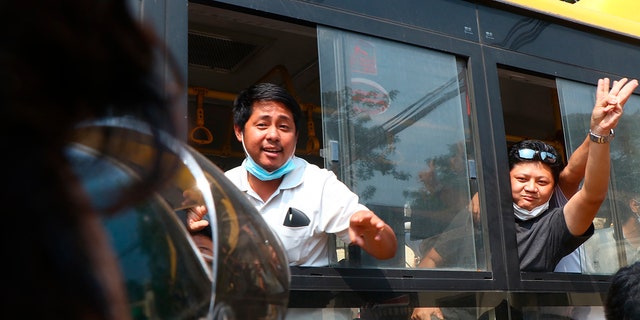 An arrested protester flashes the three-fingered salute while onboard a bus getting out of Insein prison to go to an undisclosed location Wednesday, March 24, 2021 in Yangon, Burma. (AP Photo)