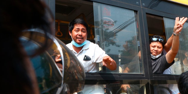 An arrested protester flashes the three-fingered salute while onboard a bus getting out of Insein prison to go to an undisclosed location Wednesday, March 24, 2021 in Yangon, Burma. (AP Photo)