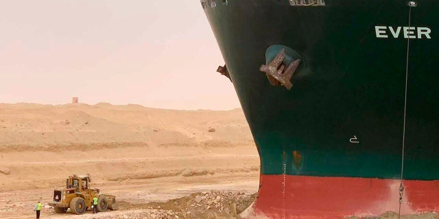 In this photo released by the Suez Canal Authority, a freighter, named MV Ever Given, sits with its bow stuck in the wall on Wednesday, March 24, 2021 (Suez Canal Authority via AP)