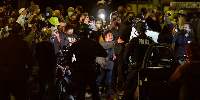 Homeless residents of Echo Park confront Los Angeles Police officers moving in to remove residents in the Echo Park Lake homeless encampment in Los Angeles late Wednesday, March 24, 2021. (Associated Press)