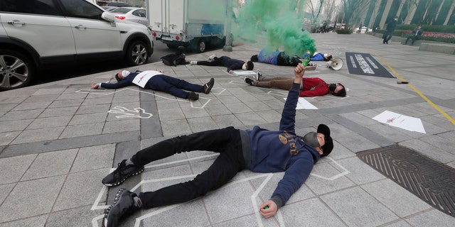 South Korean peace activists lie on a street to pay tribute to the victims of the recent protests in Burma, during a rally against Burma's military coup in Seoul, South Korea, Friday, March 26, 2021. (AP Photo/Ahn Young-joon)